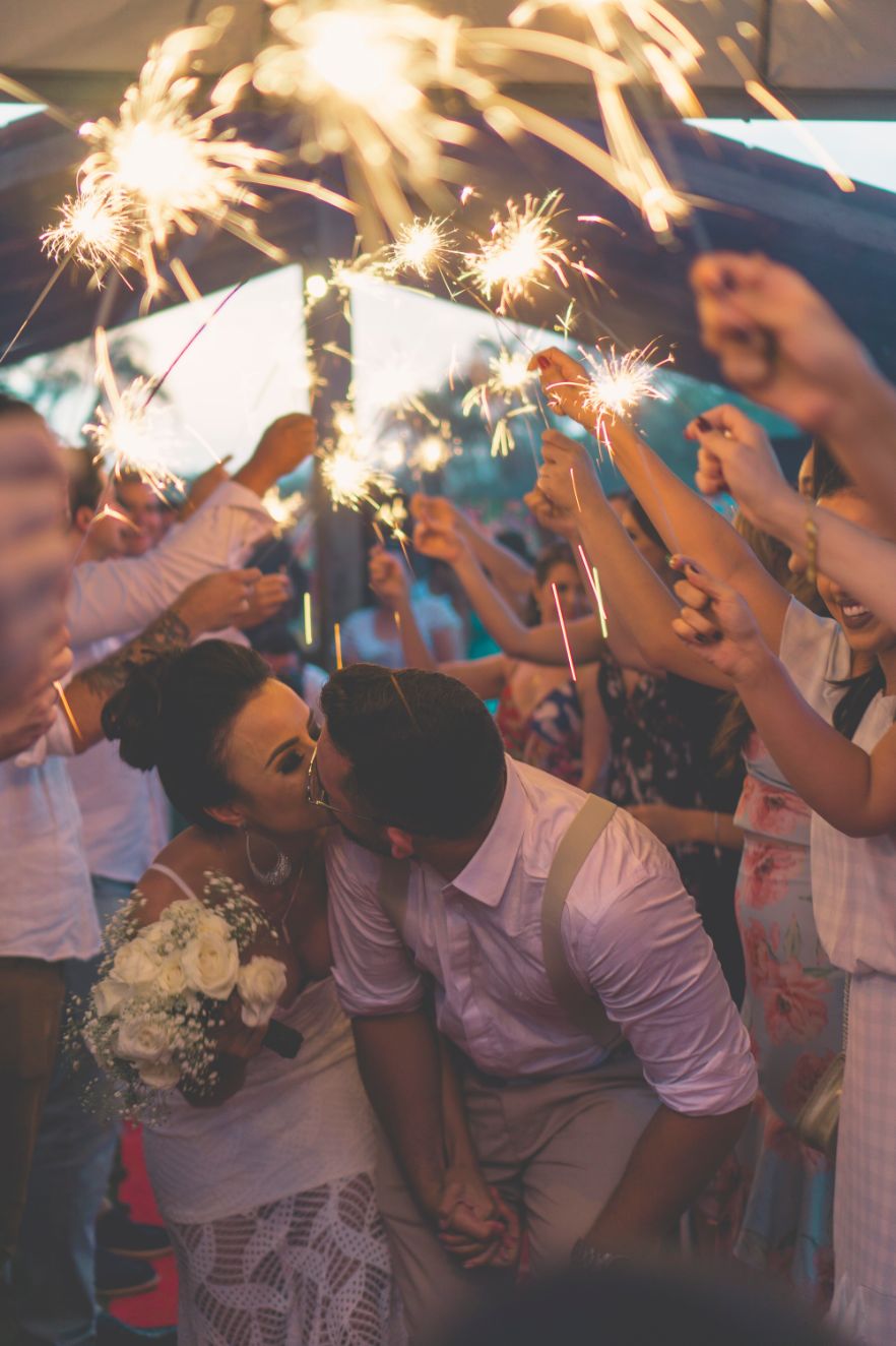A bride and groom sharing a passionate kiss surrounded by twinkling sparklers, while being serenaded by the talented DJs in Edmonton.