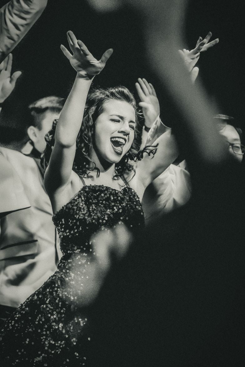 A black and white photo of a woman with her arms up in the air, taken by a talented Edmonton DJ.