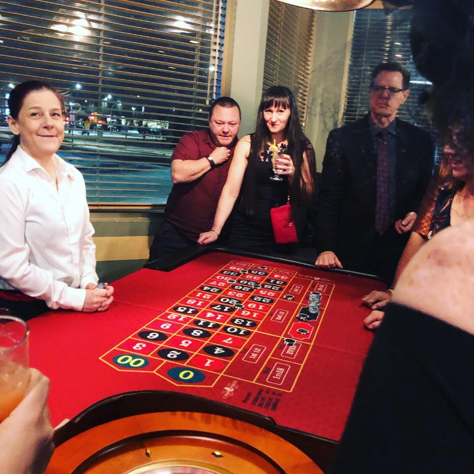 A group of people standing around a roulette table in Alberta.